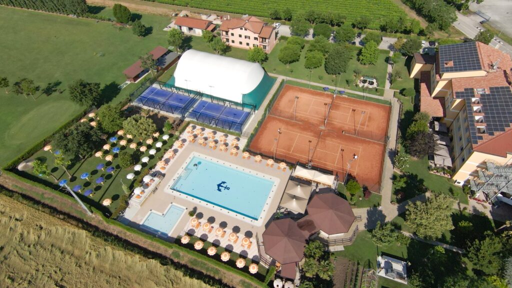 View of a resort area with a swimming pool, tennis and padel courts, and a cozy kiosk, designed for relaxation, sports, and leisure